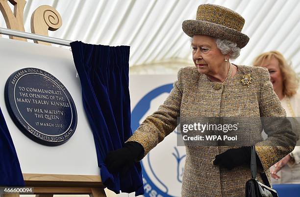 Britain's Queen Elizabeth II unveils a plaque to offically open the Mary Tealby dog kennels at Battersea Dogs and Cats Home in London on March 17,...