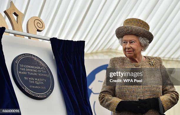 Britain's Queen Elizabeth II unveils a plaque to offically open the Mary Tealby dog kennels at Battersea Dogs and Cats Home in London on March 17,...