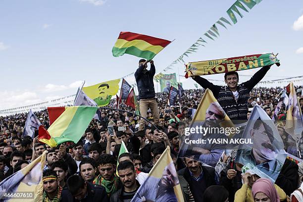 People wave Kurdish flags and flags bearing the portrait of jailed Kurdish leader Abdullah Ocalan as they celebrate Newroz, which marks the arrival...