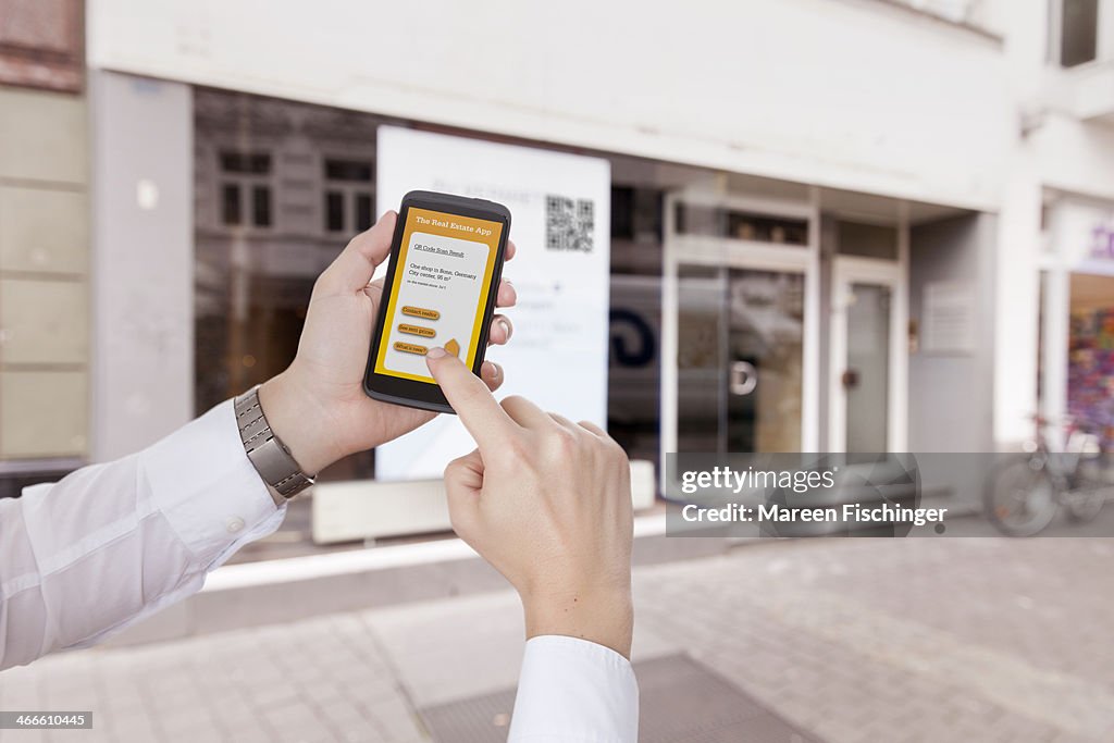 Hands holding device with real estate app in city