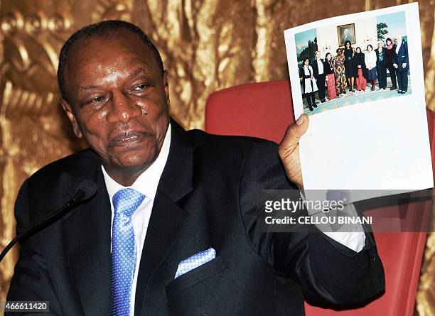 Guinean President Alpha Conde holds a picture of US First Lady Michelle Obama during a press conference on the Ebola response strategy and post-Ebola...