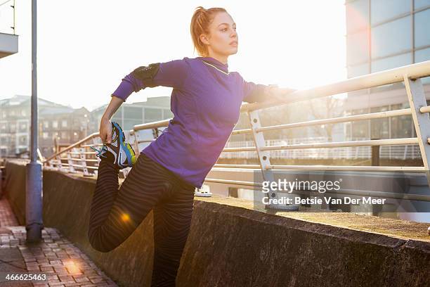 female runner stretching leg in urban space. - warm up exercise stockfoto's en -beelden