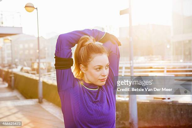 female runner stretching shoulders on street. - waist up stock pictures, royalty-free photos & images