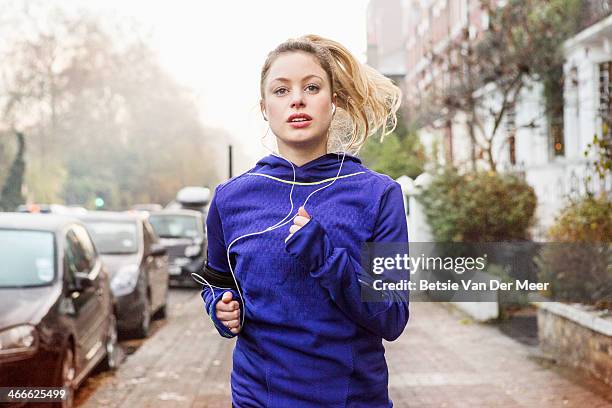 female runner running down urban street. - running gear stock-fotos und bilder