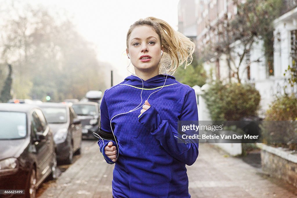 Female runner running down urban street.