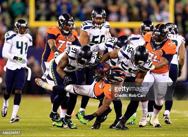 Running back Knowshon Moreno of the Denver Broncos is tackled by defensive end Chris Clemons, defensive end Cliff Avril and middle linebacker Bobby...