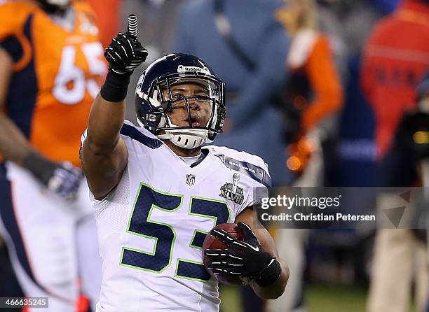 Outside linebacker Malcolm Smith of the Seattle Seahawks celebrates running back an interception off quarterback Peyton Manning of the Denver Broncos...