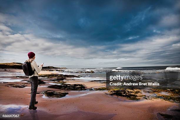 female rambler using mobile on a deserted beach - outdoor activity stock pictures, royalty-free photos & images