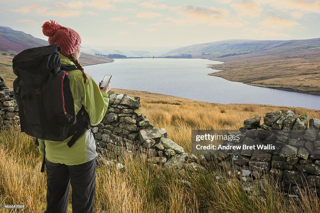 Female rambler checking GPS above lakeside