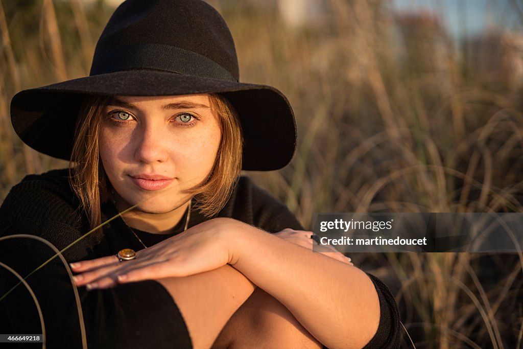 Retrato de mujer joven con sombrero en la playa al atardecer.