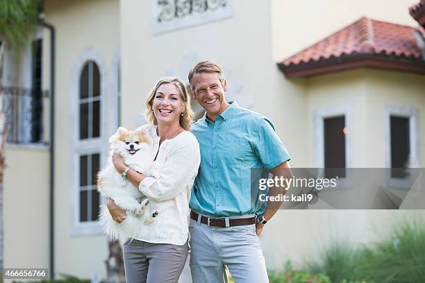mature couple standing in front of their mansion - mean dog stock pictures, royalty-free photos & images