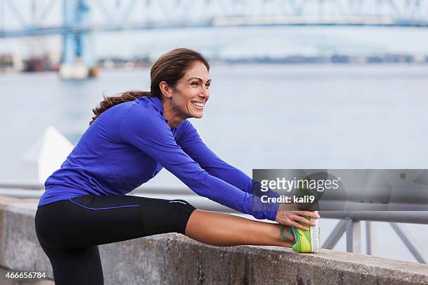 熟年女性ストレッチのジョギング中に、ウォーターフロント - running legs ストックフォトと画像