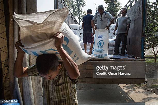 Worker carries a sac filled with rice inside one of the World Food Programme rice storage wards in the Beldangi 2 refugee camp on March 13, 2015 in...