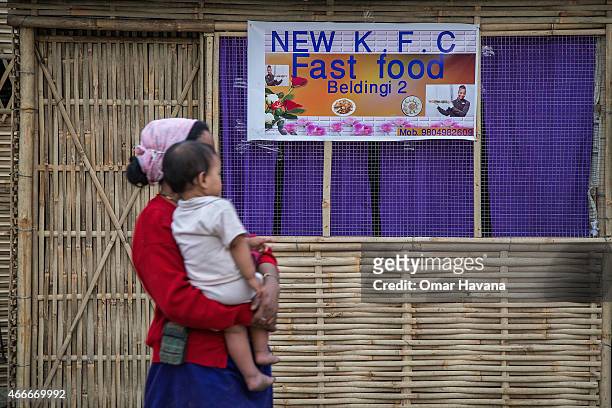 Mother holding her son passes by a fast food shop opened by refugees inside the Beldangi 2 refugee camp on March 14, 2015 in Beldangi, Nepal. More...