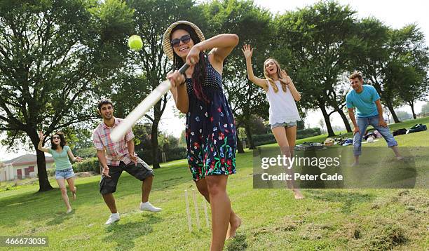 young adults playing cricket in park - cricket player stockfoto's en -beelden