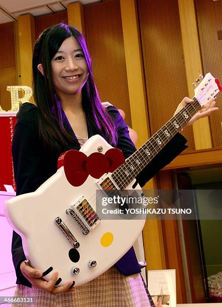 An employee of Japanese character goods maker Sanrio displays a Hello Kitty shaped guitar at an exhibition of Sanrio's products at their headquarters...