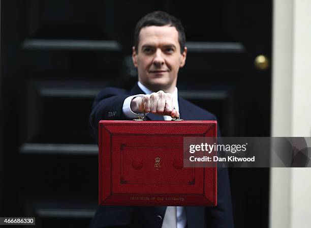 The Chancellor of the Exchequer George Osborne holds his ministerial red box up to the media as he leaves 11 Downing Street on March 18, 2015 in...