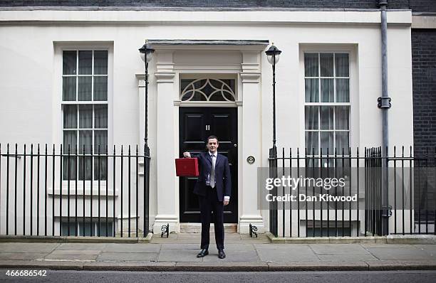 The Chancellor of the Exchequer George Osborne holds his ministerial red box up to the media as he leaves 11 Downing Street on March 18, 2015 in...