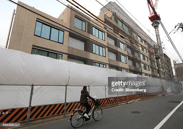 Woman cycles past the Parkhouse Grand Minamiaoyama Takagicho residential building, developed by Mitsubishi Jisho Residence Co., a unit of Mitsubishi...