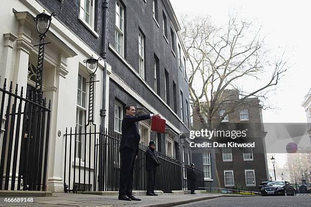 The Chancellor of the Exchequer George Osborne holds his ministerial red box up to the media as he leaves 11 Downing Street on March 18, 2015 in...