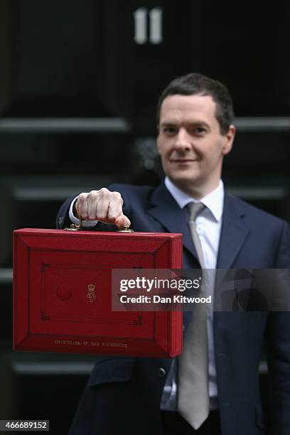 The Chancellor of the Exchequer George Osborne holds his ministerial red box up to the media as he leaves 11 Downing Street on March 18, 2015 in...