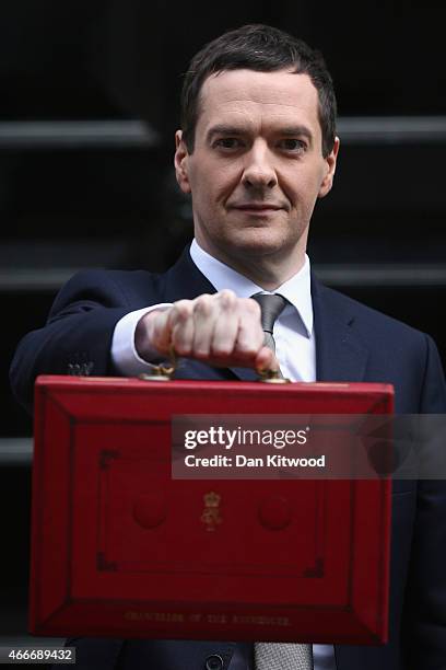 The Chancellor of the Exchequer George Osborne holds his ministerial red box up to the media as he leaves 11 Downing Street on March 18, 2015 in...