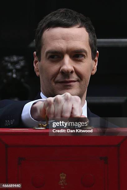 The Chancellor of the Exchequer George Osborne holds his ministerial red box up to the media as he leaves 11 Downing Street on March 18, 2015 in...