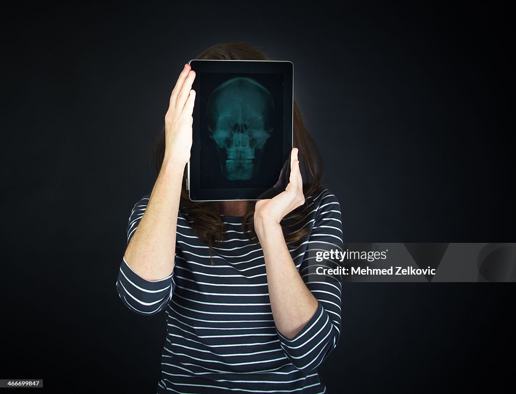 Woman holding skull x-ray on digital tablet