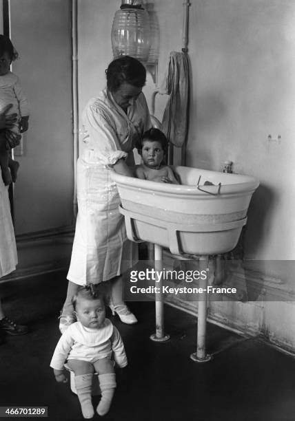 - Child minder bathing a baby at the day nursery of department store les Galeries Lafayette, in May 1929 in Paris, France.