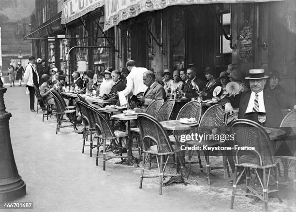 People sitting at sidewalk cafe during the heat wave, in July 1929 in Paris, France.