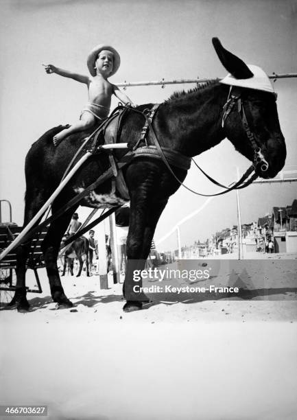 Circa 1950: Young boy riding a donkey on a beach, circa 1950 in United Kingdom.