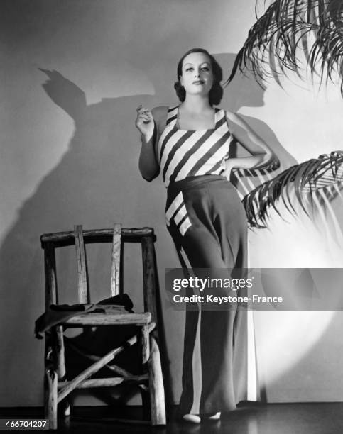 American Actress Joan Crawford, known as the first college girl of America, poses in a pair of indoor red and white pajamas that she wore in her...