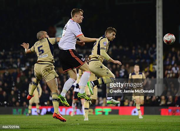 Matt Smith of Fulham outjumps Giuseppe Bellusci and Gaetano Berardi of Leeds United during the Sky Bet Championship match between Fulham and Leeds...