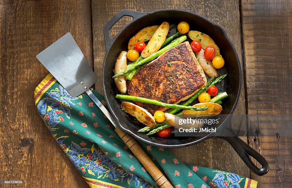 Salmão assado e legumes em uma frigideira de ferro fundido.