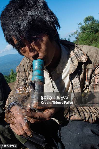 Drug addict smokes opium with his makeshift pipe made with bamboo, a plastic tube and a rifle cartridge. The whole Palaung area is plagued by the...