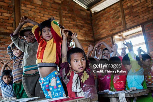Children have to raise their arms in order to avoid making noise while their teacher is teaching another group in a Palaung village school.