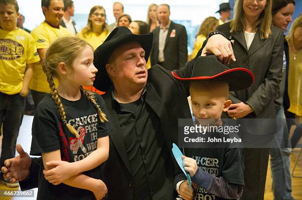 Garth Brooks fixes Levi Foreman 6 years old, cowboy hat for a photo op with his sister Abigail Foreman 9 years old at Childrens Hospital to Celebrate...