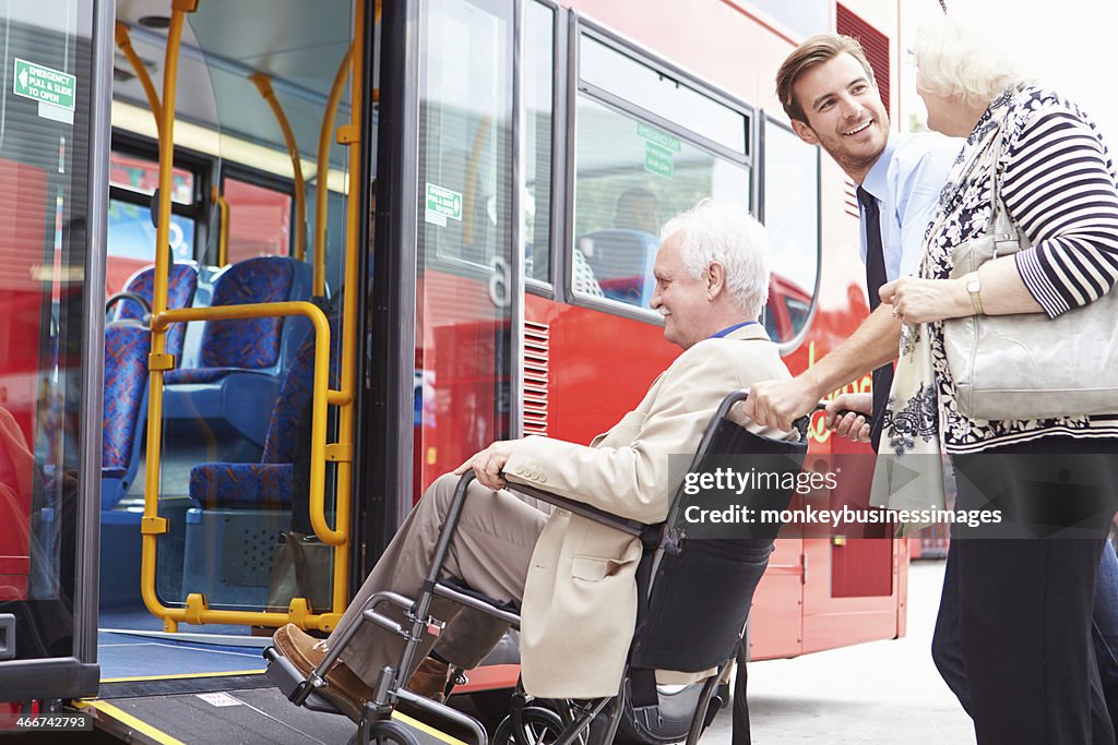 Motorista ajudando sênior casal, pegue o ônibus Via rampa de cadeira de rodas