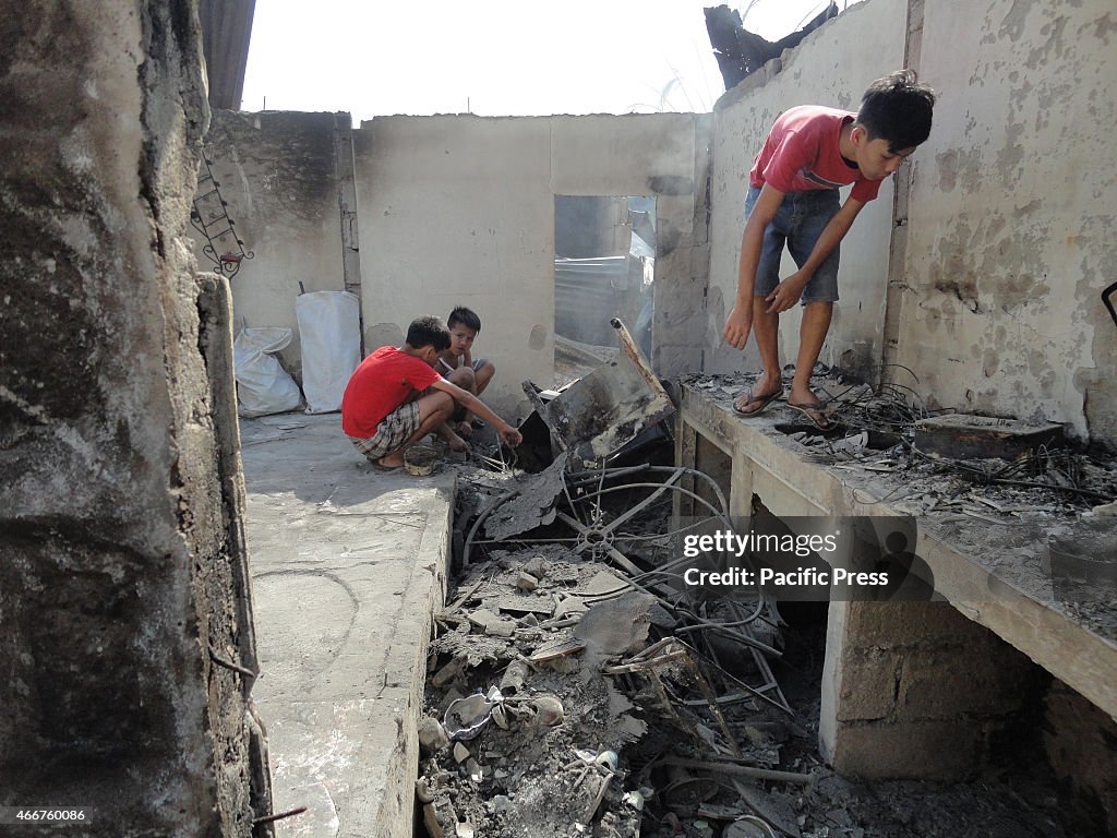 Filipino children look for salvageable materials in a razed...