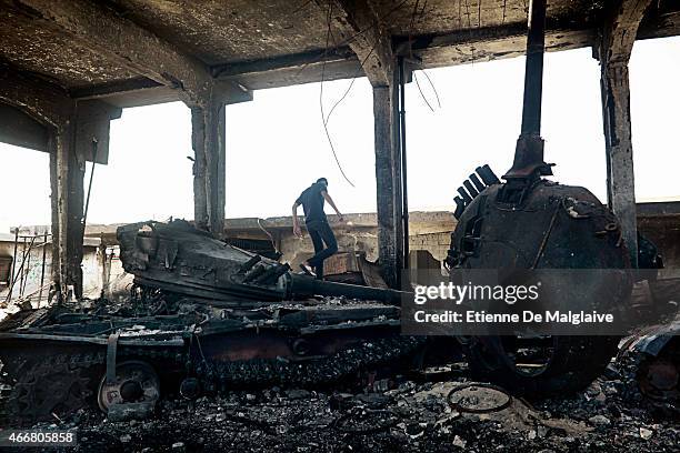 Misrata inhabitants walk around what remained of Gadhafi's army tanks that were destroyed by NATO air strikes. These three tanks were hiding under a...