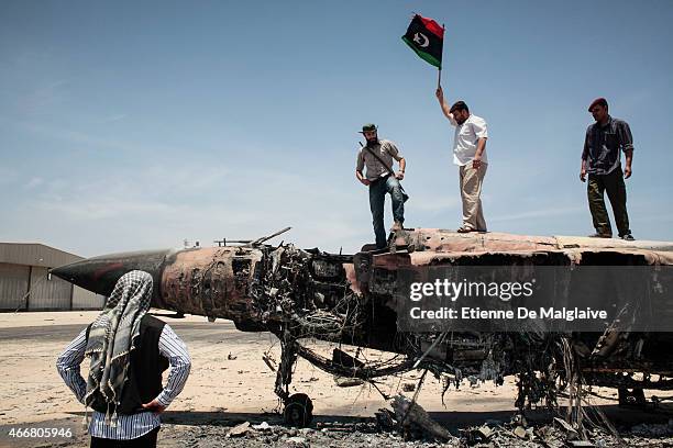 Rebels fighters stand atop a Libyan air force fighter jet MiG-23 destroyed by a NATO strike in March on Misrata airport. 28 May 2011.