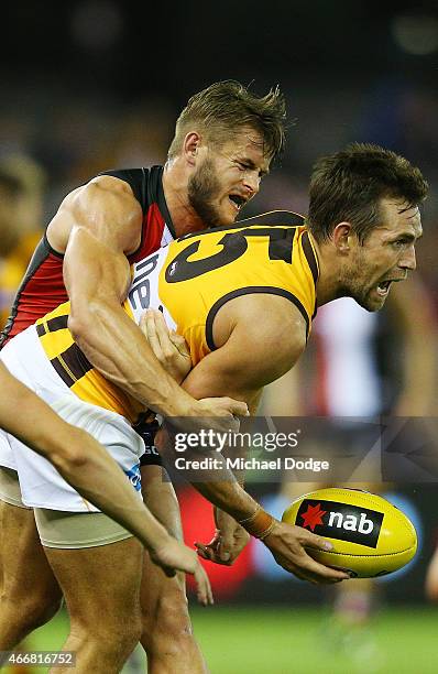 Luke Hodge of the Hawks handballs away from Maverick Weller of the Saints during the NAB Challenge AFL match between St Kilda Saints and Hawthorn...