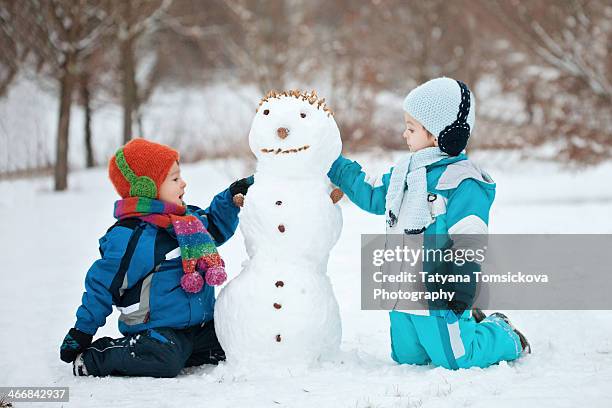 two boys, playing with a  snowman - schneemann bauen stock-fotos und bilder