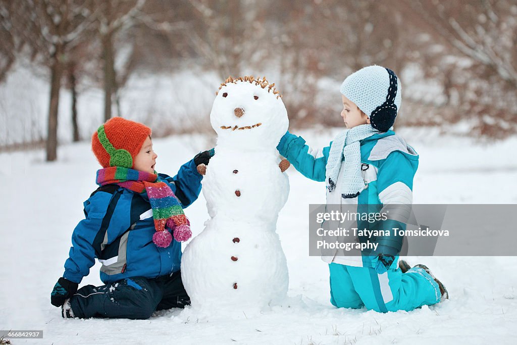 Two boys, playing with a snowman