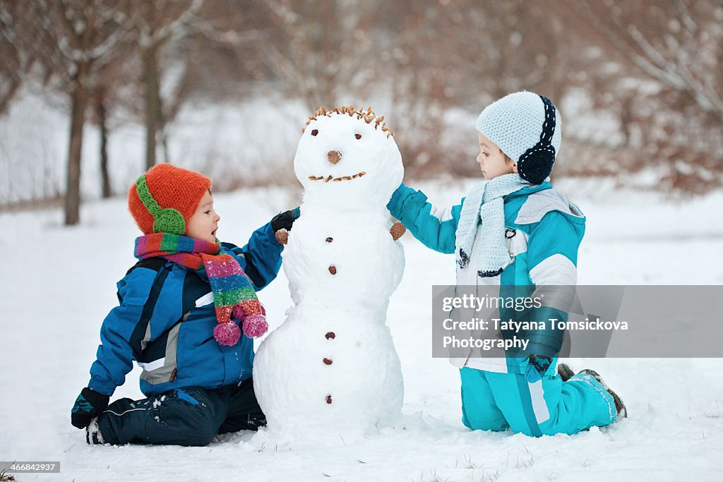 Two boys, playing with a  snowman