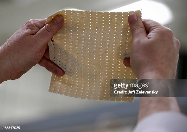 Rabbi Yaakov Horowitz examines the holes in a sheet of unbaked matzo from the matzo production line at the Manischewitz manufacturing facility on...