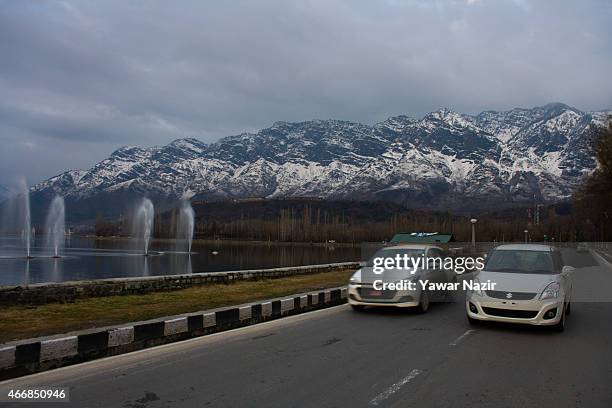 Vehicles drive on the boulevard past snow capped Zabarvan mountains on March 19, 2015 in Srinagar, the summer capital of Indian administered Kashmir,...