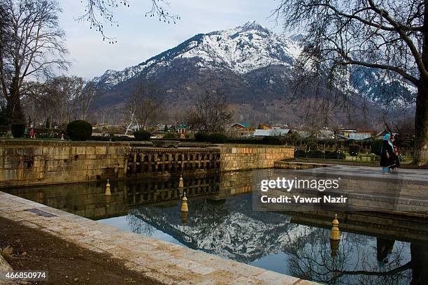 Snow capped Zabarvan mountains are reflected in the Shalimar Mughal garden fountains on March 19, 2015 in Srinagar, the summer capital of Indian...