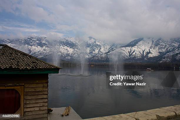 Kashmiri man rows his Shikara near the snow capped Zabarvan mountains on March 19, 2015 in Srinagar, the summer capital of Indian administered...