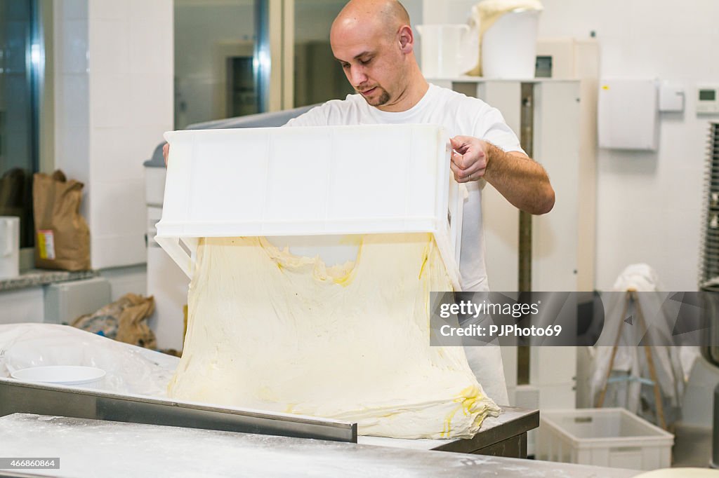 Baker putting leavened dough on working table